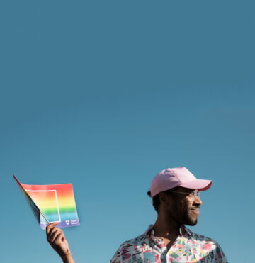 Person mit rosa Kappe und LGBTIQ-Fahne der Fensterl Parade.